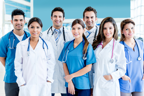 Picture of Physicians and Nurses. There is two male Physicians, two female Physicians, one male Nurse, and two female Nurses. They are all smiling and standing next to each other.