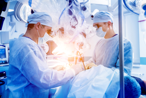 Picture of a surgical team in an operation room performing surgery. There is two males.