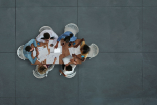 Picture of four females and two males sitting down at a table and talking.